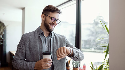 Relaxed system administrator happily looks at his watch and enjoys the fact that he can use his time wisely