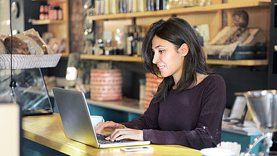 Lady working with laptop at bar counter in café