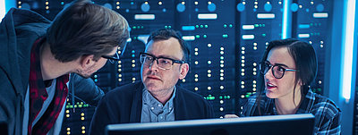 Young IT employees show their boss in the server room how to optimize network security