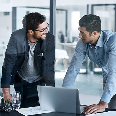 Two administration employees have an animated conversation on laptop in office about the digital sovereignty of their company