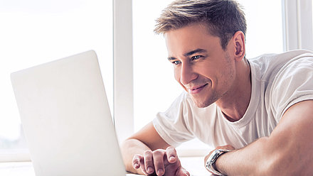 Happy-relaxed young man observes with pleasure the effects of his optimized WLAN on his laptop