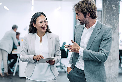 Middle-aged Asian boss listens enthusiastically to idea from younger employee as they both leave a meeting situation