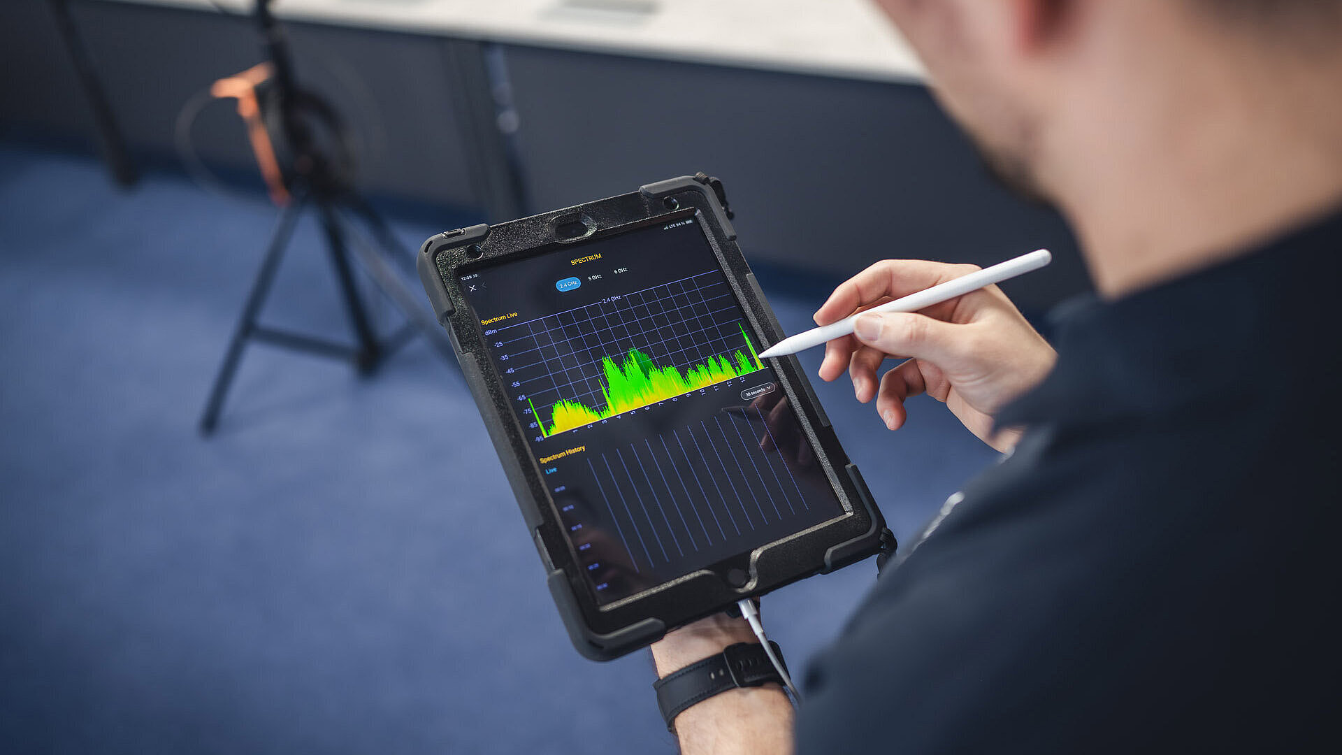 Mann am Tablet mit Stift in der Hand, zu sehen ist ein Frequenzspektrum in grün