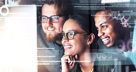 Three IT staff members look at the screen with delight