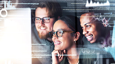 Three IT staff members look at the screen with delight