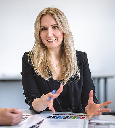 A woman presents a topic at the table with several colleagues