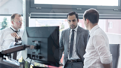 Three businessmen in shirts and suits consult with each other on how to quickly and sensibly implement the new EU directive NIS2 on network and information security in their company