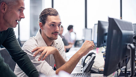 Two men looking at a screen and talking