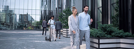 Glass facade of an office complex with employees walking past it