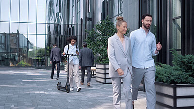 Glass facade of an office complex with employees walking past it
