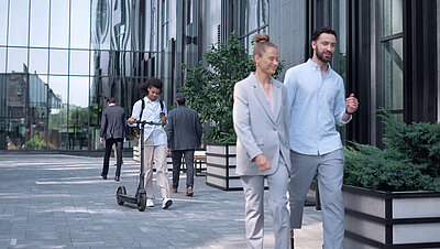 Glass facade of an office complex with employees walking past it