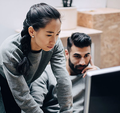 Young, Asian IT employee with pigtail shows two colleagues how they can better digitalize their processe