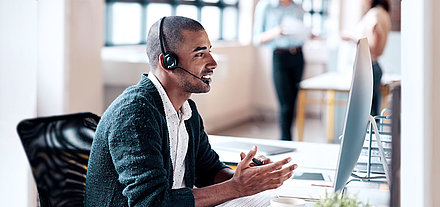 Office worker sits in front of PC and makes phone call