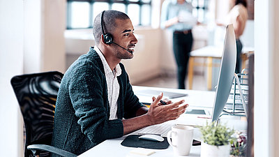 Office worker sits in front of PC and makes phone call