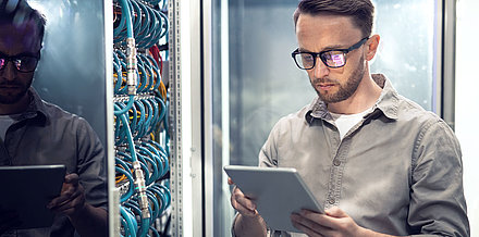 IT employee checks security settings on tablet in server room