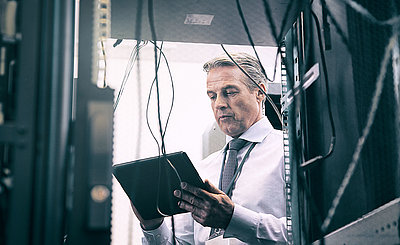 Managing director uses a tablet to check the functionality of the IT network 