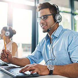 Friendly sales staff with headset take customer call in office