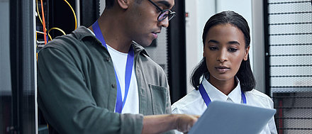 Male and female IT administrators confer on laptop in server room for better network management