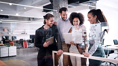 Group of young office workers looking at a laptop together in modern office