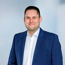 Portrait photo of LANCOM employee René Martin: Friendly, middle-aged man with blue eyes, smart smile and short hair in a suit