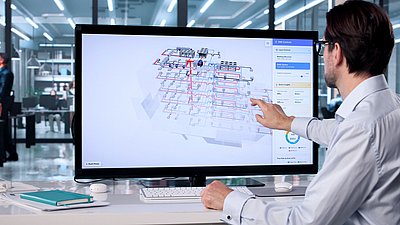 Photo: Person sitting in front of a large monitor displaying a digital building and network model and interacting with the visualization using touch gestures.