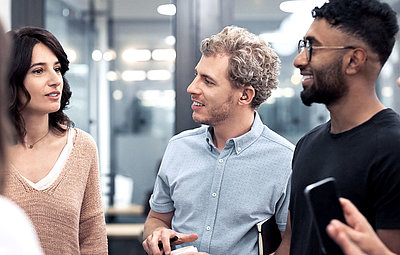 Group of young men and women converses animatedly in modern authority