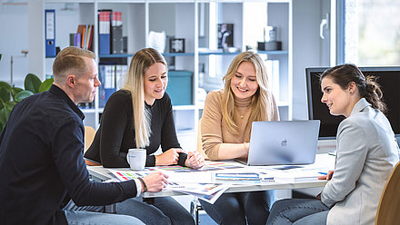 Meeting with four people together at the table equipped with laptop and color tables