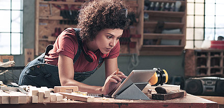 Woman standing in a factory workshop using a tablet