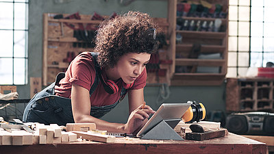 Woman standing in a factory workshop using a tablet