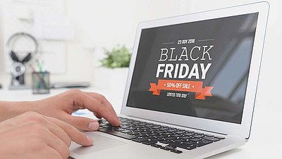 Laptop with Black Friday Sale offer on screen and two hands typing on keyboard