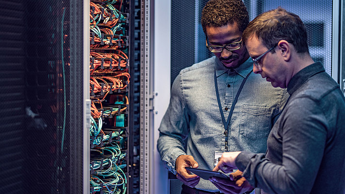 Two IT specialists check firewall in server room