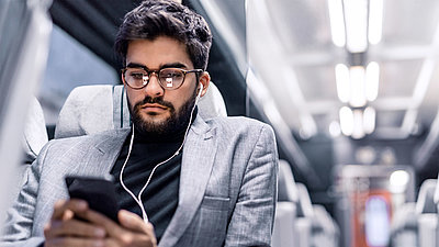 Man in train compartment with cell phone in hand