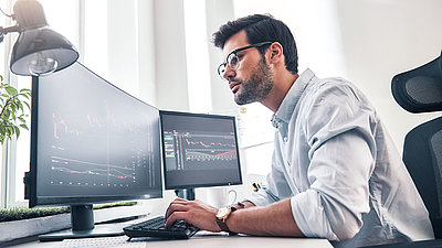 Network administrator sits in front of two screens and monitors his network