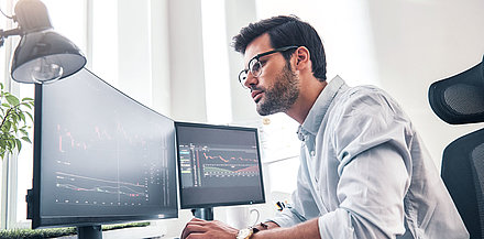 Network administrator sits in front of two screens and monitors his network