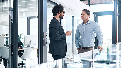 Two security experts confer on glass office gallery