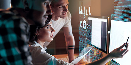 One female and two male IT employees monitor their network on a dashboard