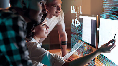 One female and two male IT employees monitor their network on a dashboard