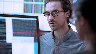 IT employee checks programming code on PC screen for hacker attacks