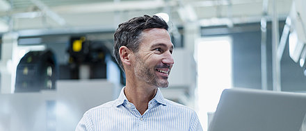 Smiling man looking to the right with laptop in hand