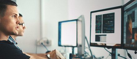 Young IT employee in front of PC screen