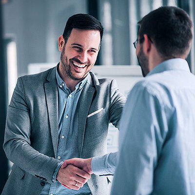 Two men in suits shake hands in a spirit of partnership