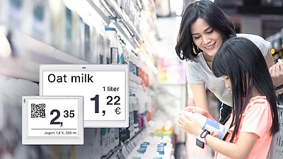 Asian lady fetches an orange juice with her daughter from the refrigerators of a supermarket, the prices are displayed on Wireless ePaper Displays from LANCOM