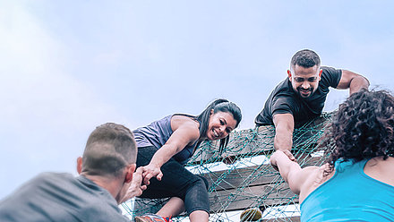 Four people overcome an obstacle and support each other