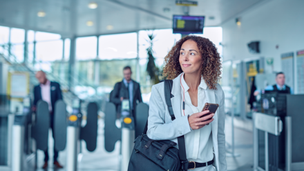 Woman with cell phone in hand looking left at an airport 