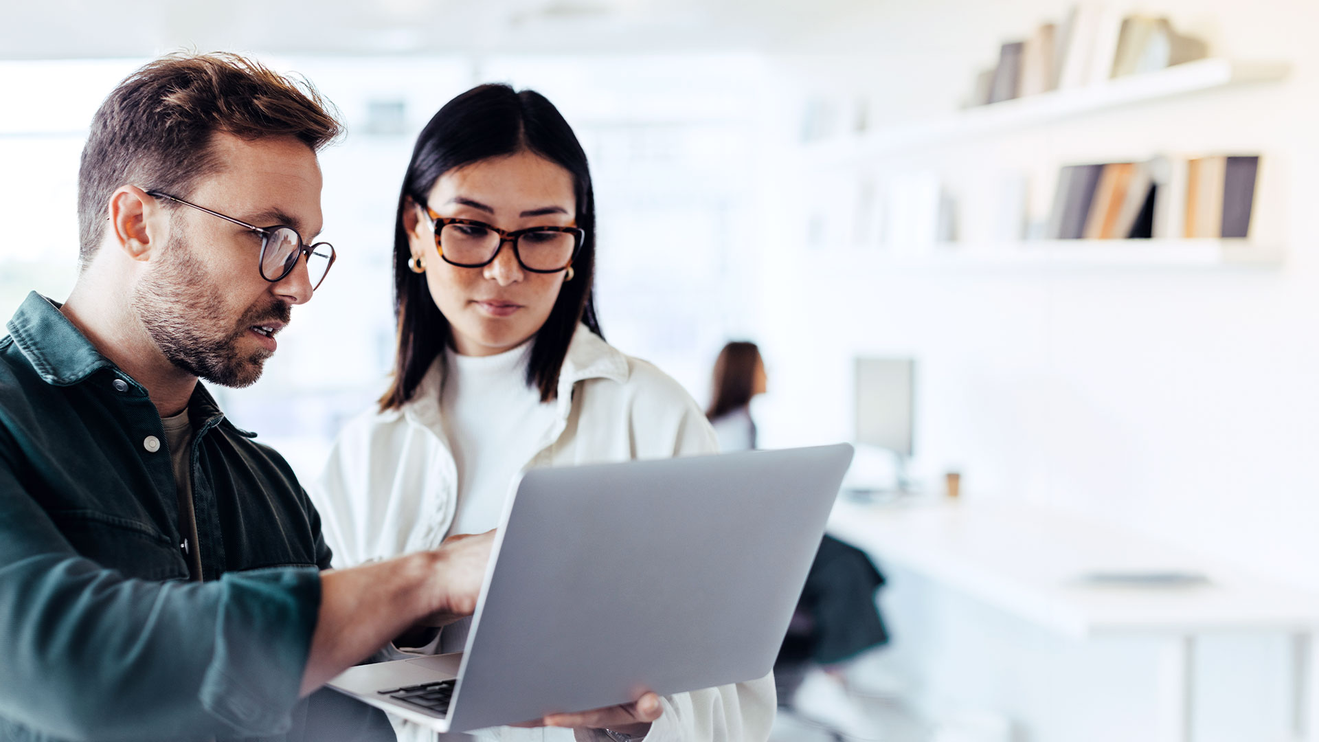 Man and woman look together at the screen of a laptop